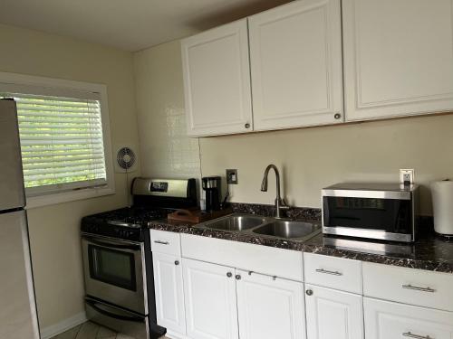 eine Küche mit weißen Schränken, einer Spüle und einer Mikrowelle in der Unterkunft Gaia House in Annapolis