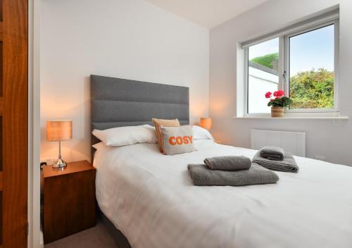 a bedroom with a large white bed with a window at 78 Cae Du in Abersoch