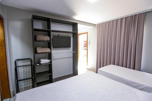 a hotel room with two beds and a tv at Vila Nóbrega Residencial in Foz do Iguaçu