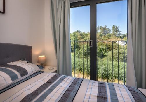 a bedroom with a bed and a view of a balcony at 7 Pen y Bont in Abersoch