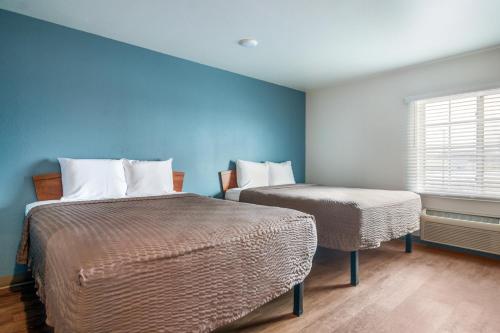 two beds in a room with blue walls and a window at Extended Stay America Select Suites - Cleveland - Avon in Avon
