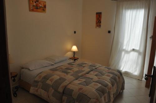 a bedroom with a bed with a lamp and a window at Résidence La Galiote in Essaouira