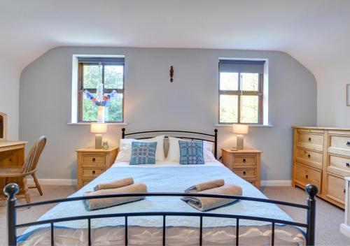 a bedroom with a bed and two windows at Aberelwyn Mill in Llanglydwen