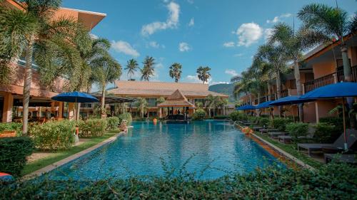 a swimming pool in front of a resort with palm trees at Chivatara Resort Bang Tao Beach Phuket - SHA in Bang Tao Beach