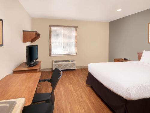a bedroom with a bed and a desk with a television at Extended Stay America Select Suites - Fayetteville - West in Fayetteville