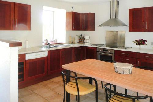eine Küche mit Holzschränken und einem Holztisch in der Unterkunft Holiday Home Plouégat-Guérand - BRE05042-F in Plouégat-Guérand