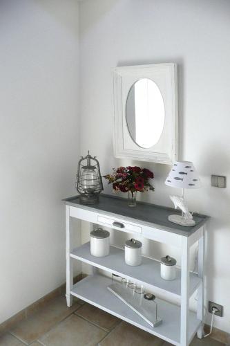 une console blanche avec un miroir et des fleurs dans l'établissement Stone House in Brittany near Morlaix Bay, à Plouégat-Guérand