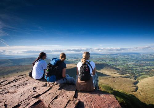 three people sitting on the edge of a mountain at Bedlwyn Coch Farm in Cray