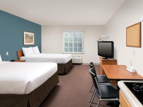 Habitación de hotel con 2 camas, escritorio y TV. en Extended Stay America Select Suites - Tallahassee - Northwest, en Tallahassee