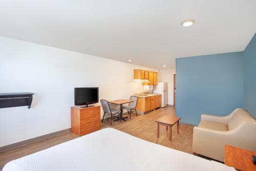 a room with a bed and a living room with a kitchen at Extended Stay America Select Suites - Phoenix - Peoria - Sun City in Peoria