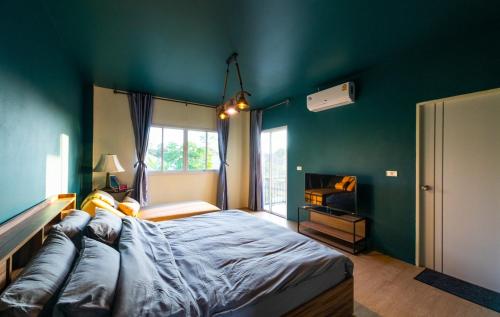 a bedroom with a large bed and a green wall at Amaz Villa in Ban Nang Lae