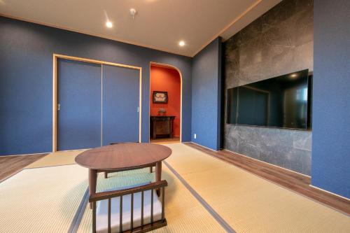 a room with blue walls and a table and a tv at Yufuin Tsubaki in Yufuin