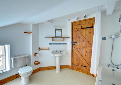 a bathroom with a wooden door and a toilet and a sink at Black Patch in Norton