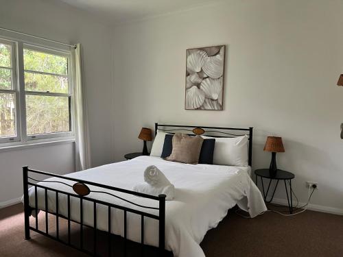 1 dormitorio con 1 cama con edredón blanco en Giants Table and Cottages, en Maydena