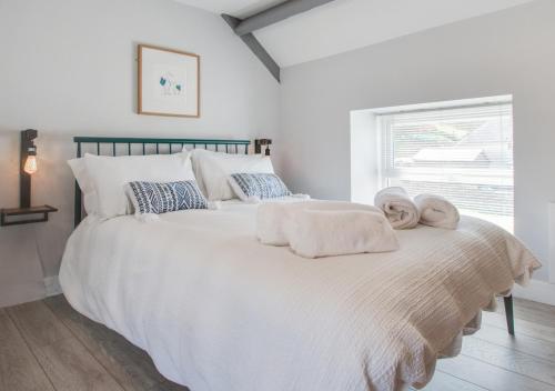 a bedroom with a large white bed with towels on it at Bwthyn Bach in Ferryside