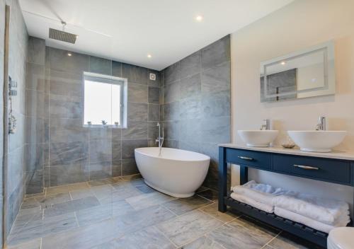 uma casa de banho com 2 lavatórios, uma banheira e um chuveiro em Bryn Y Mor em Parkmill