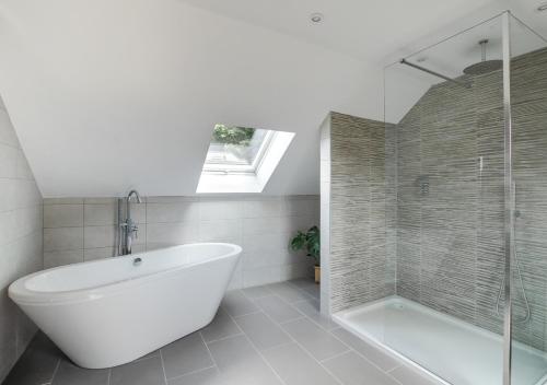 a bathroom with a bath tub and a shower at Bwthyn Clyd in Llanddyfnan