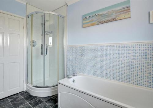 サンダースフットにあるCarreg Morのバスルーム(シャワー、白いバスタブ付)