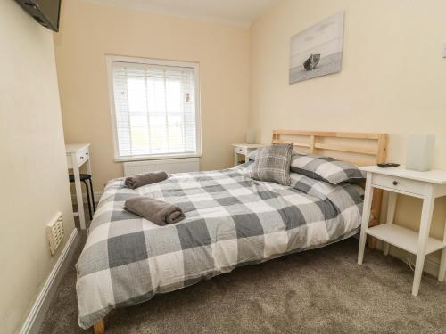 a bedroom with a bed with a plaid blanket at 2 Lane End Cottages in Hull