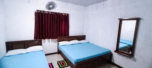 a room with two beds and a mirror in it at Serene Homestay in Anuradhapura