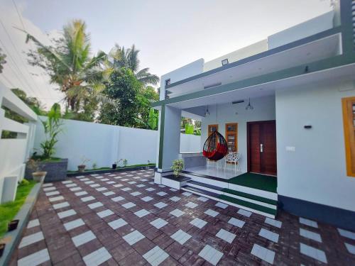 a house with a courtyard with a white wall at Milaano Orchids, Service Villa, Kammana Mananthavady in Wayanad
