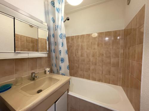 een badkamer met een wastafel, een spiegel en een bad bij Appartement Jullouville, 1 pièce, 2 personnes - FR-1-361-10 in Jullouville-les-Pins