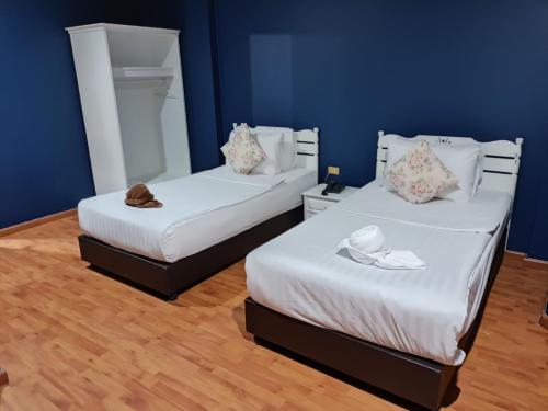 two beds in a room with blue walls at Rimtarn Hotel Pakchong in Pak Chong