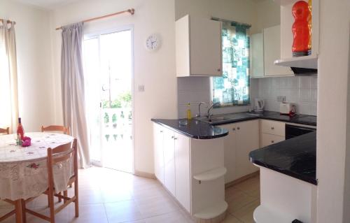 a kitchen with white cabinets and a table and a window at Constantia Gardens Apartments in Paphos City