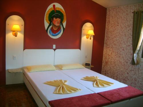 a bedroom with a large bed with a painting on the wall at Pousada Santa Anna in Itaipuaçu