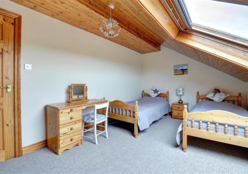 a bedroom with two beds and a desk and a window at Tyn Coed in Moelfre