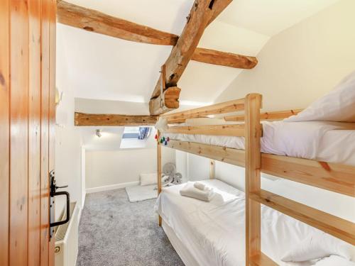 two bunk beds in a room with wooden beams at Barn On The Wall in Walton