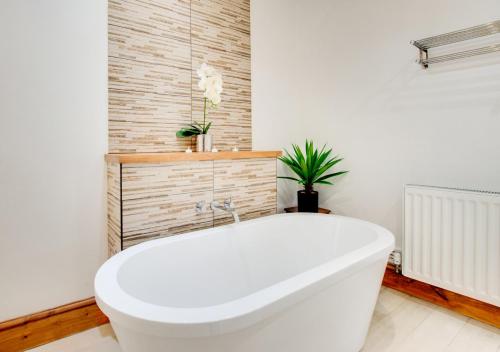 a white bath tub in a bathroom with a plant at The Lodge in Pwllheli