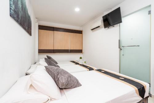 a bedroom with a bed with white pillows and a tv at Tai Hoe Hotel in Singapore