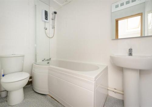 a white bathroom with a toilet and a sink at Glanaber Bach in Abersoch