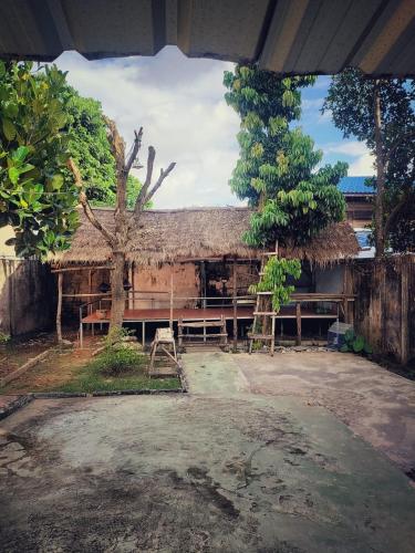 a building with a straw roof and a tree at Naga Hostel & Café in Thakhek