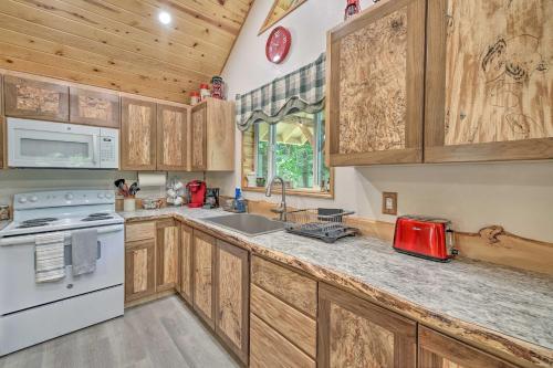 a kitchen with wooden cabinets and a white appliance at Wandering Elk Cabin Retreat with Golf Access! in Packwood