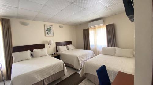 a hotel room with two beds and a window at Real Guanacaste in San Pedro Sula