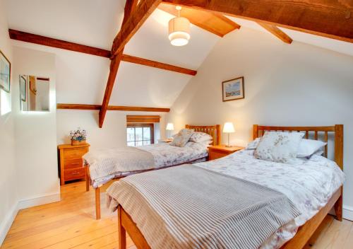 2 camas en una habitación con techos de madera en Maggies Cottage, en Begelly