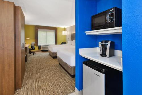 um quarto de hotel com um quarto com uma cama e uma televisão em Holiday Inn Express & Suites Chesapeake, an IHG Hotel em Chesapeake