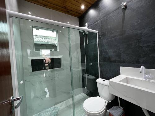 uma casa de banho com um chuveiro, um WC e um lavatório. em Moradas Desterro, próximo ao aeroporto 24 em Florianópolis