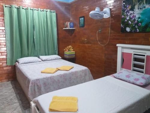 two beds in a room with green curtains at Casa Lagoa Piscina in Araruama