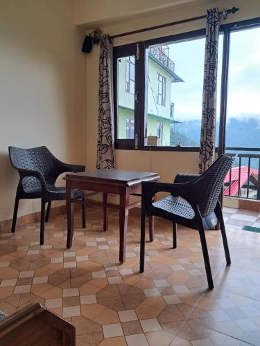 a table and chairs in a room with a window at Anand Niketan Homestay Shimla in Shimla