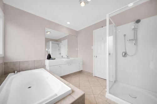 W łazience znajduje się wanna, prysznic i umywalka. w obiekcie Cheerful 4 bedrooms home with stunning sunshine w Auckland