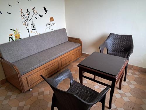 a bed and two chairs and a table in a room at Anand Niketan Homestay Shimla in Shimla