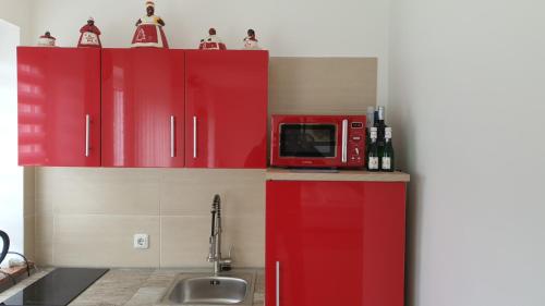 ベルヒテスガーデンにあるFerienwohnung da Celiaの赤いキャビネットと赤い電子レンジ付きのキッチンが備わります。