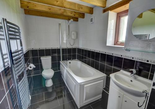 a bathroom with a sink and a tub and a toilet at Holly Cottage in Haverfordwest