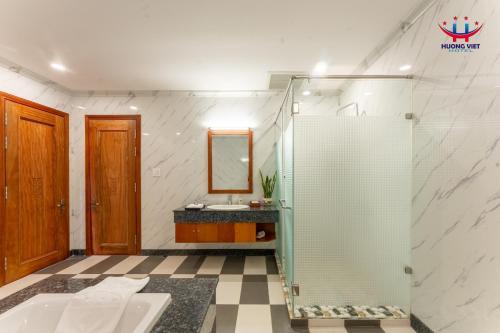 a bathroom with a shower with a sink and a mirror at Huong Viet Hotel Quy Nhon - Beachfront in Quy Nhon