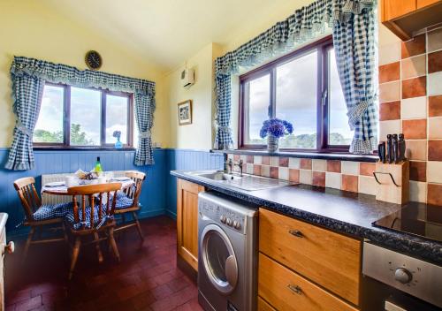 a kitchen with a washing machine and a table with chairs at Ty Eiddew in Caernarfon