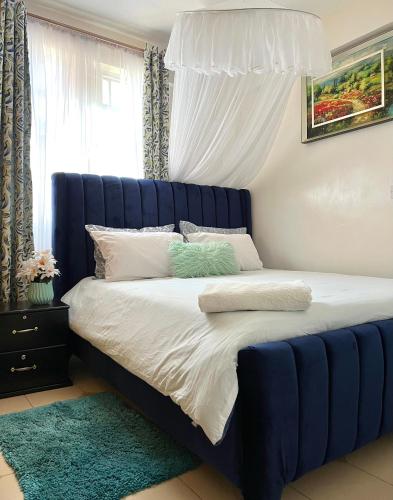a bed with a blue headboard in a bedroom at Cozy 1br milimani in Kisumu