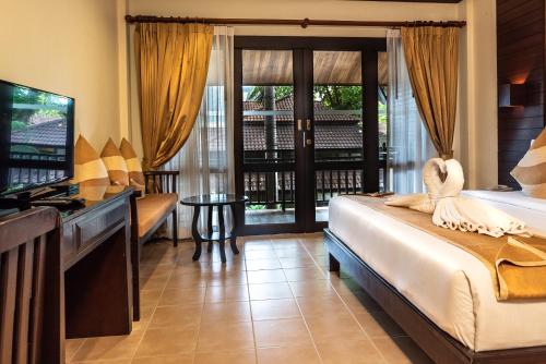 a bedroom with a bed and a television and a balcony at Am Samui Palace in Lamai